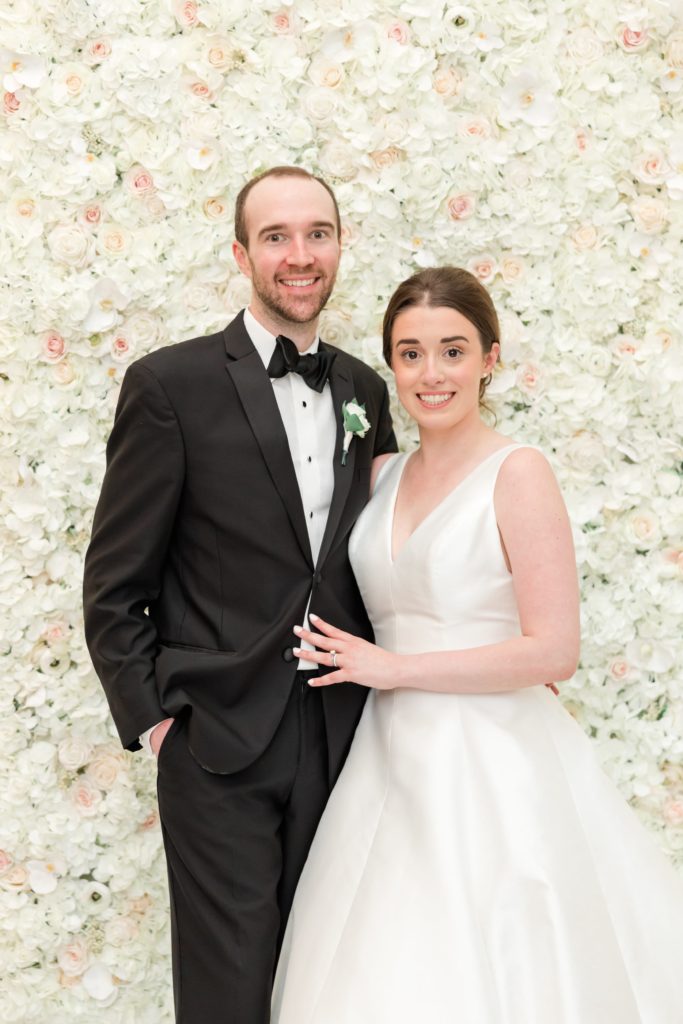 Bride and groom in front of flower backdrop