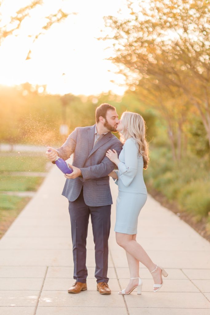 Guy and girl popping champagne for engagement photos