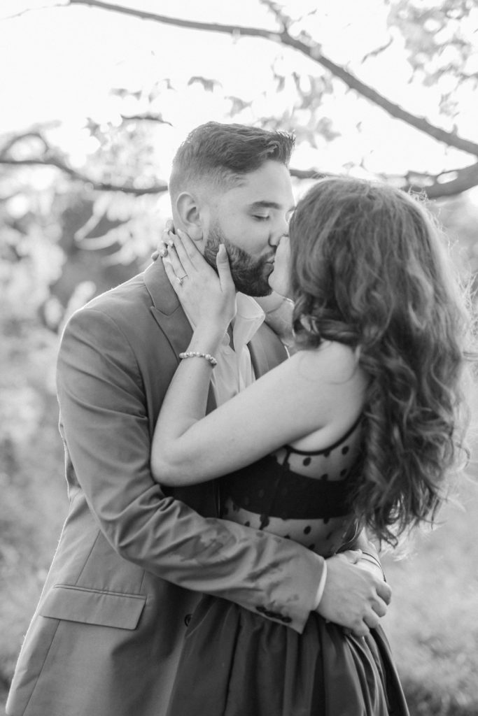 Black and white engagement portrait of couple kissing
