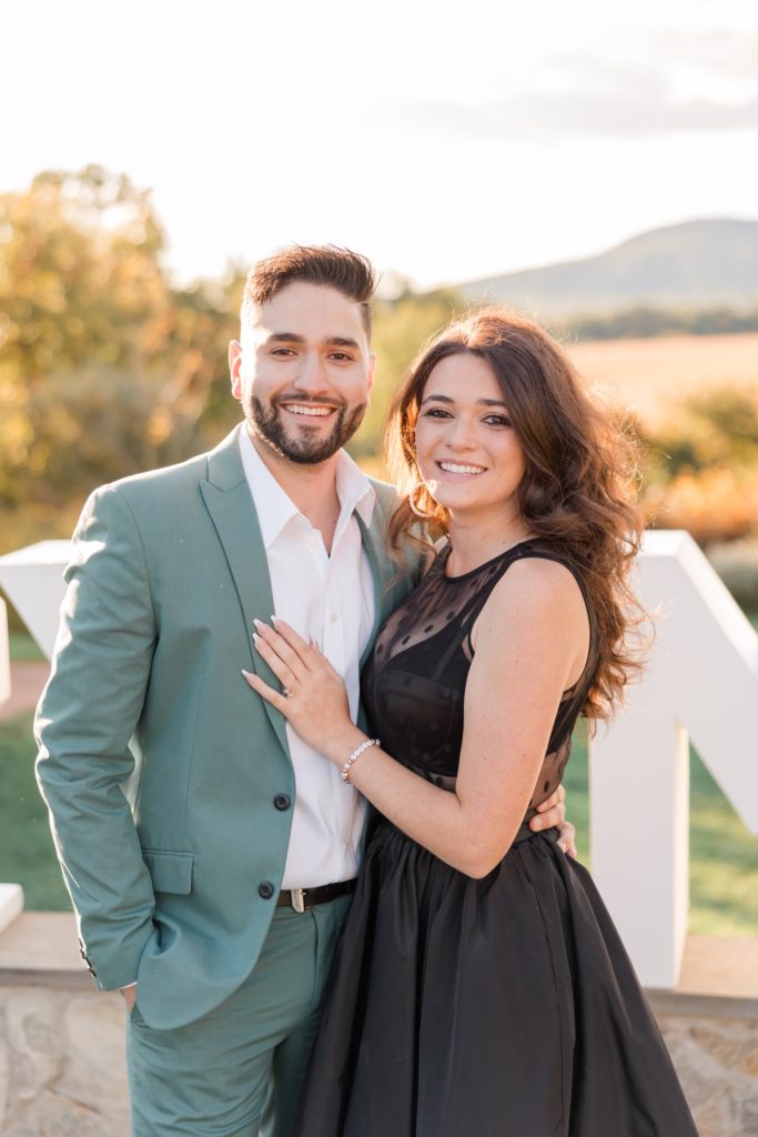 Engagement portrait of a guy in green suit & girl in black dress