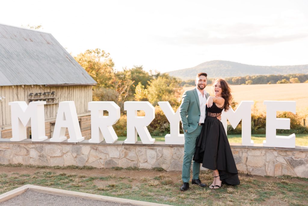 Nely engaged couple in front of Marry Me sign