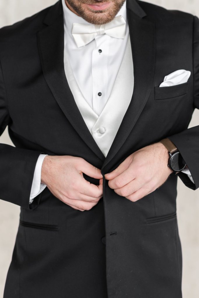 Groom wearing black tuxedo getting dressed