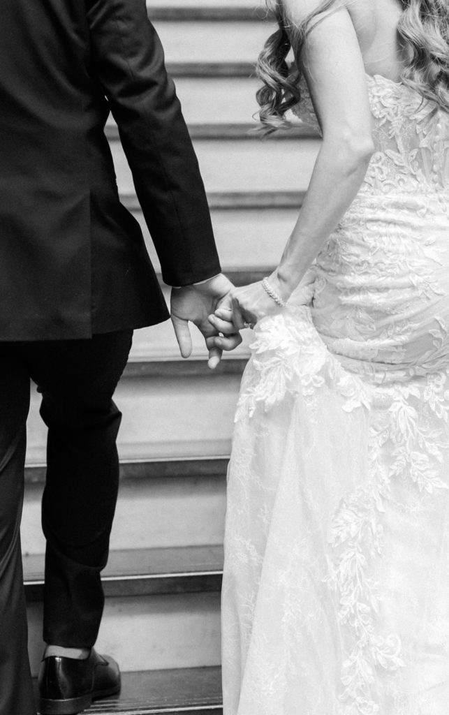 Black and white portraits of bride and groom holding hands