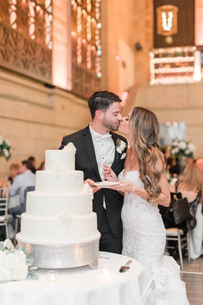 Bride and groom kissing near wedding cake