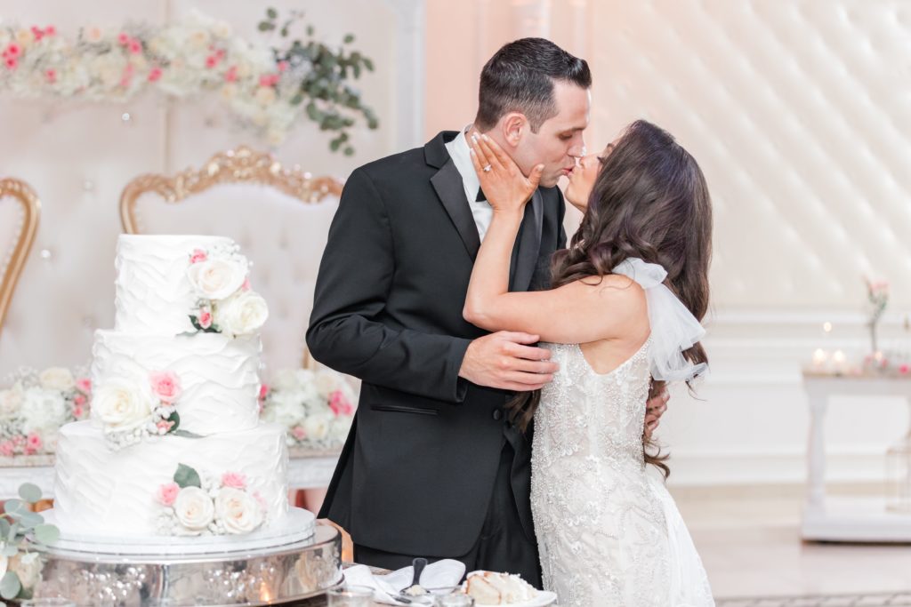 Bride and groom kissing in front of wedding cake