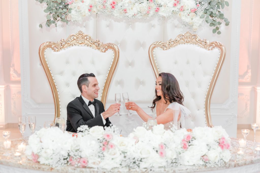 Bride and groom with champagne glasses at sweetheart table