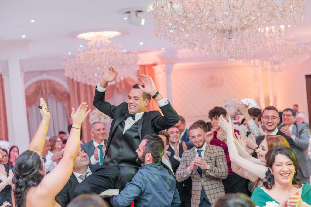 Groom carried in chair during dancing