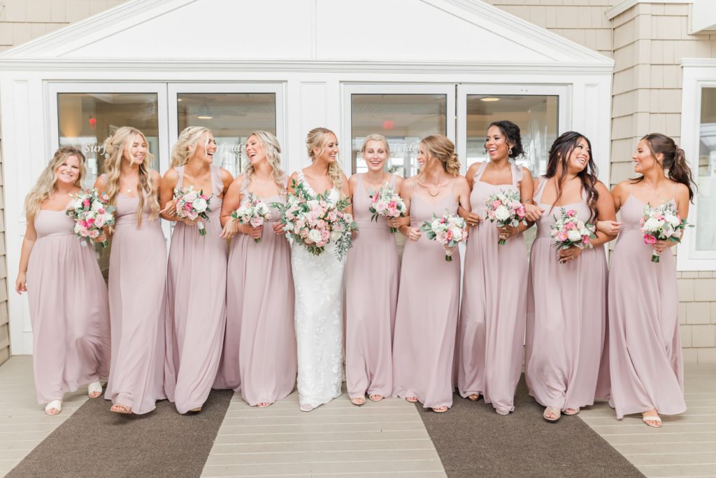 Bridesmaids in long pink bridesmaid dresses with pink and white flowers