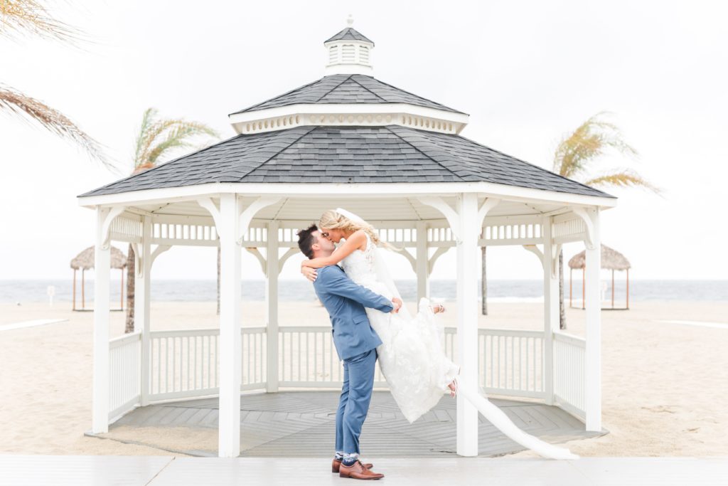 Bride and groom kissing in front of a beach gazebo