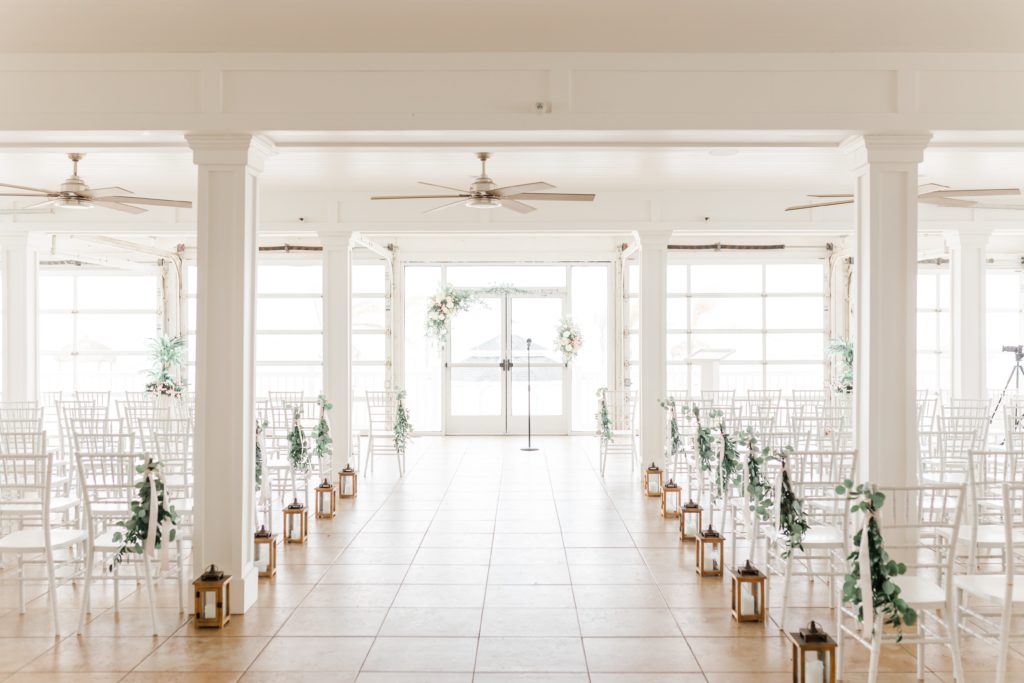 Indoor wedding ceremony with white wood chairs