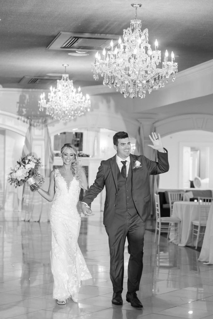 Black and white photo of bride and groom entering ballroom