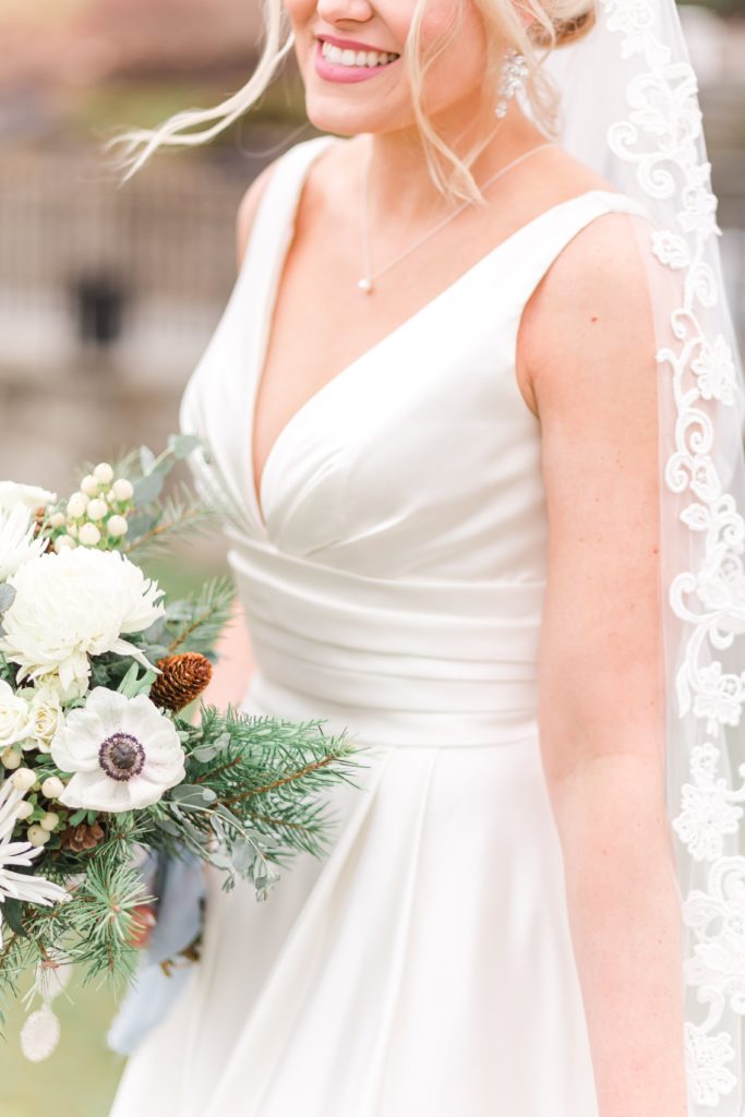 Bride in a line wedding gown with lace veil and winter bouquet