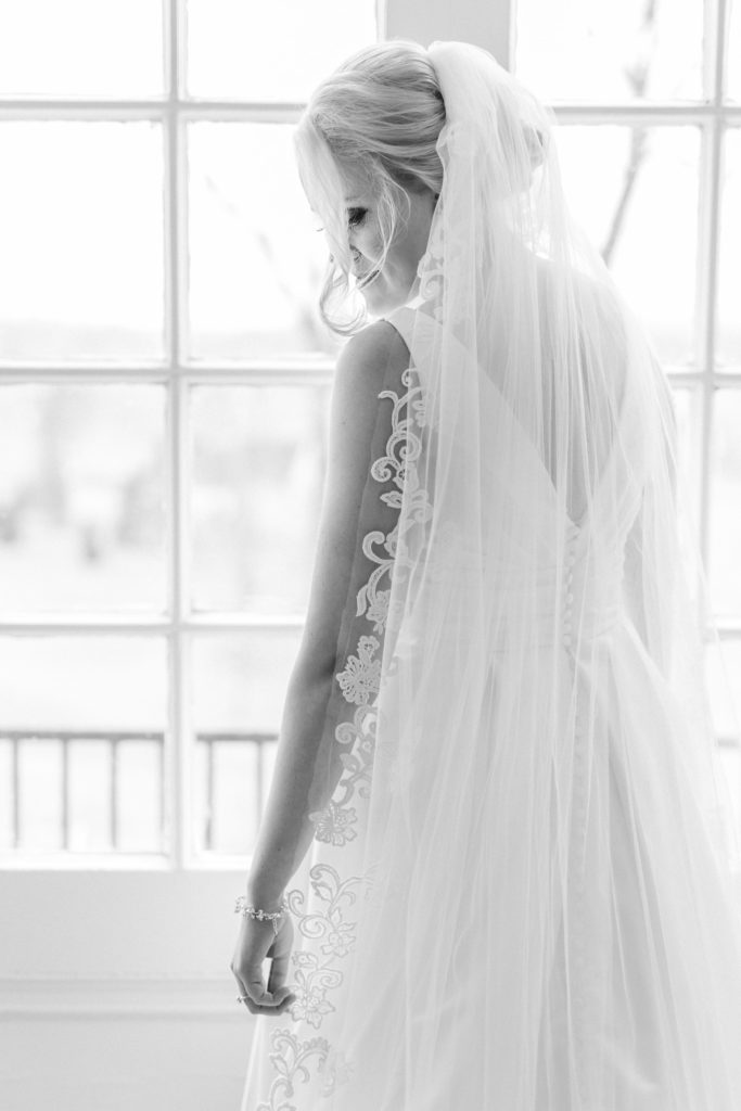 Black and white of bride in white wedding dress with lace veil