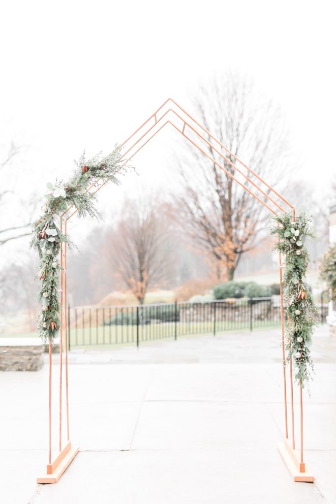 Copper wedding ceremony arch with greenery
