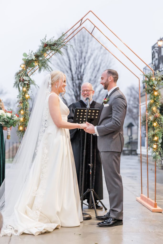 bride and groom under copper ceremony backdrop