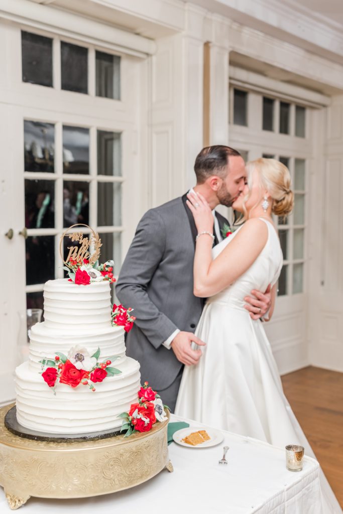 Bride and groom kissing behind wedding cake