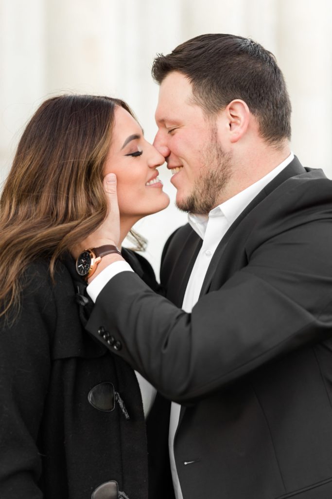 Couple in black jackets kissing during engagement photos