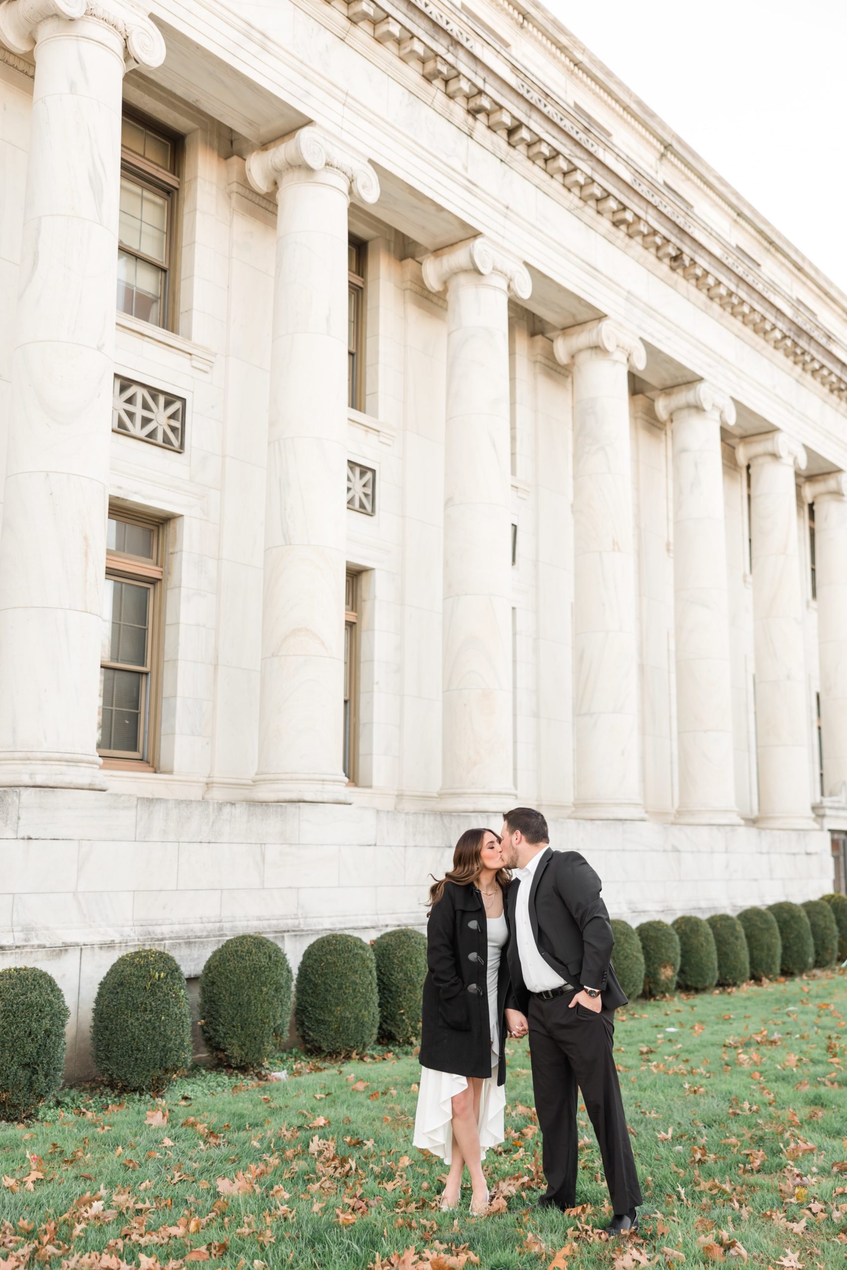 Couple in black jackets kissing during engagement photos at Delware County courthouse