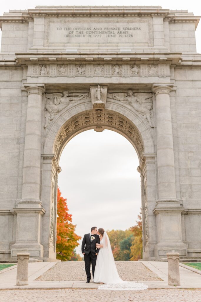 Bride and groom kissing under park arch