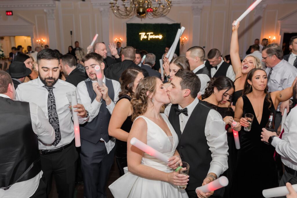 Bride and groom kissing on crowded dance floor